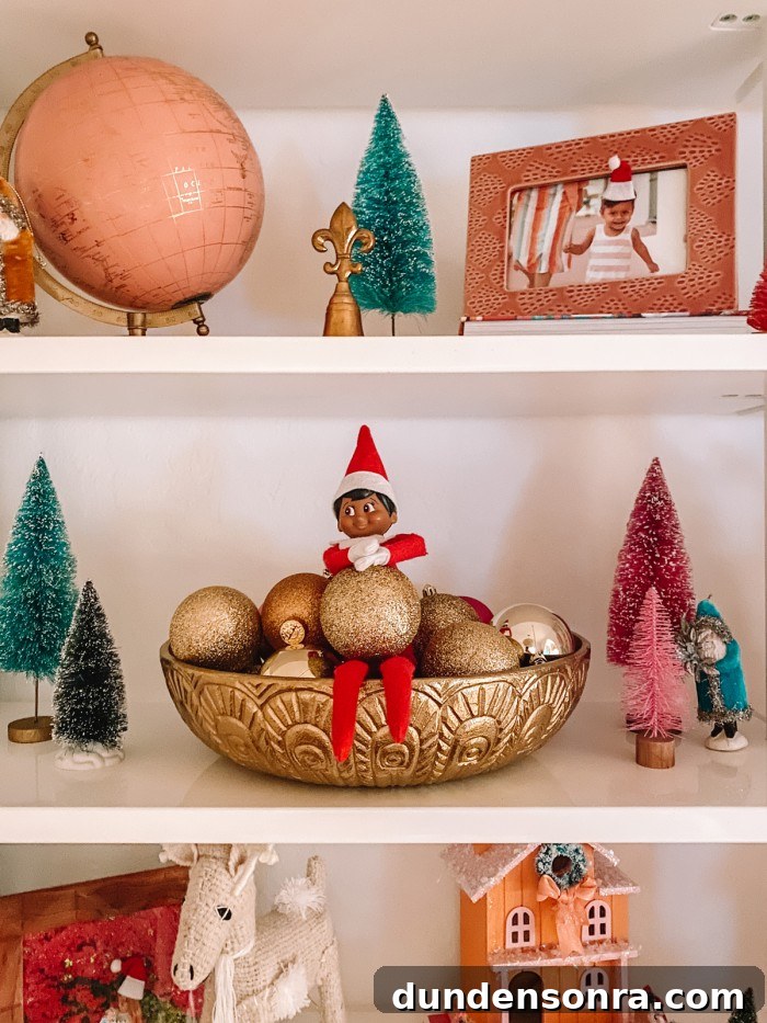 Elf on the Shelf sitting in bowl of ornaments on shelf