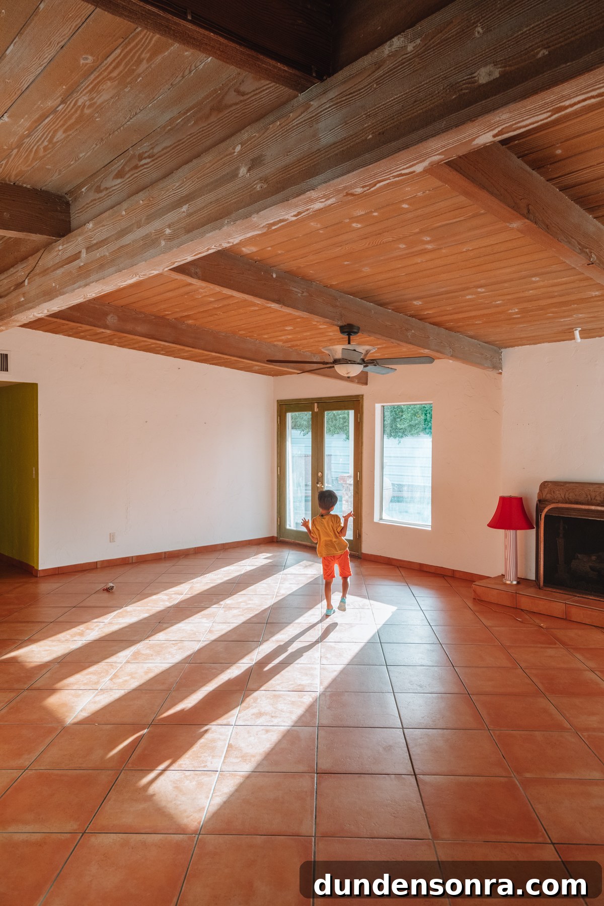 Child in empty house with wood beamed ceilings and sunlight