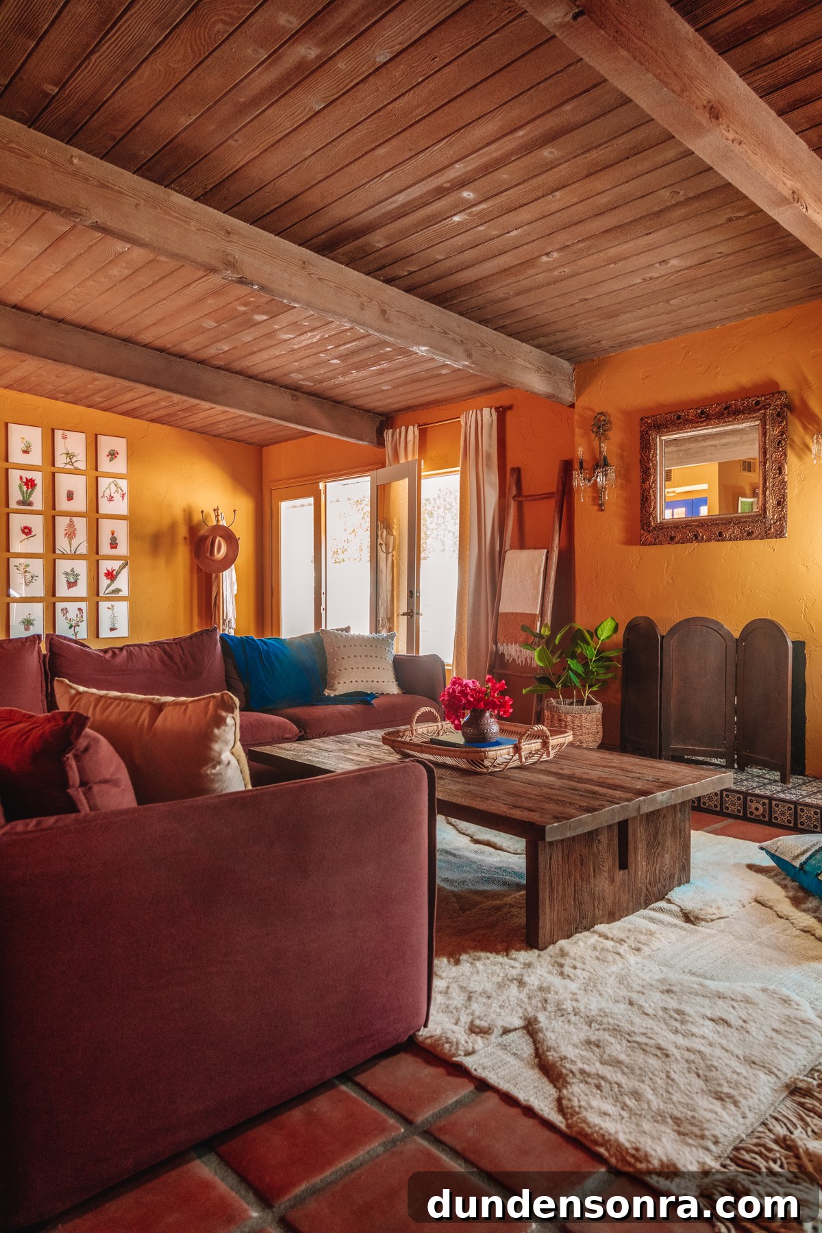 Plum couch with white rug in an ochre living room