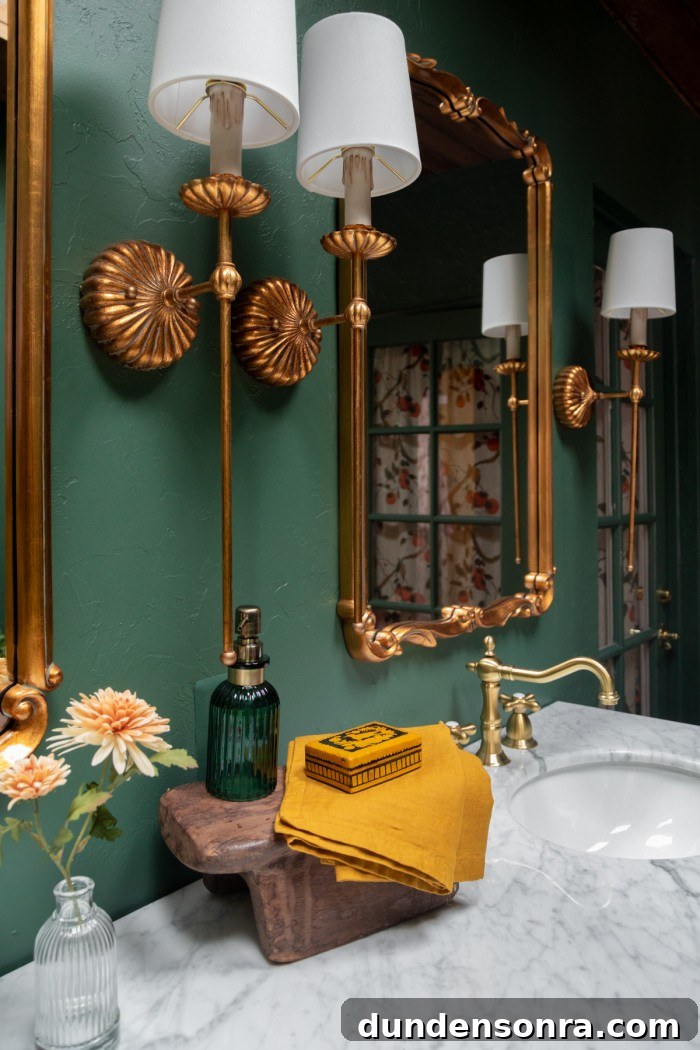 Brass lights and mirrors in green bathroom