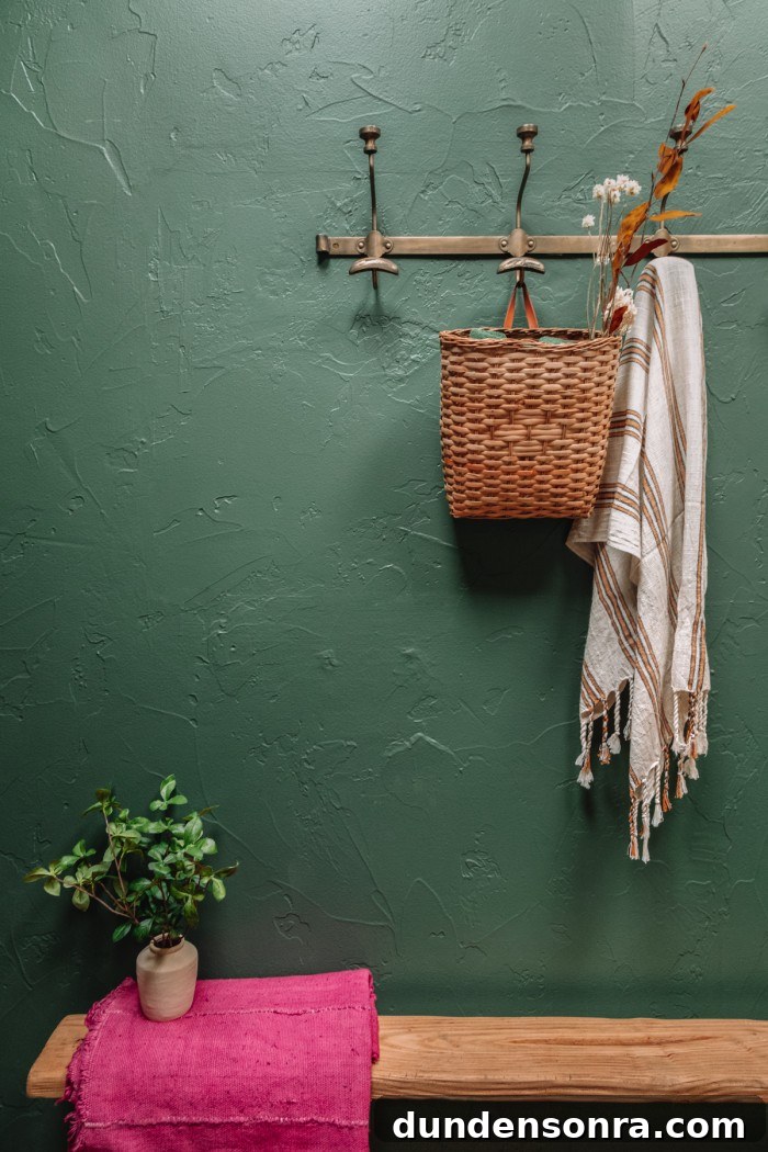 Bench on green wall with brass hooks above
