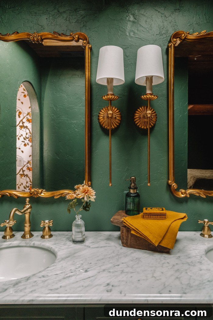 Green bathroom with brass sconces and mirrors