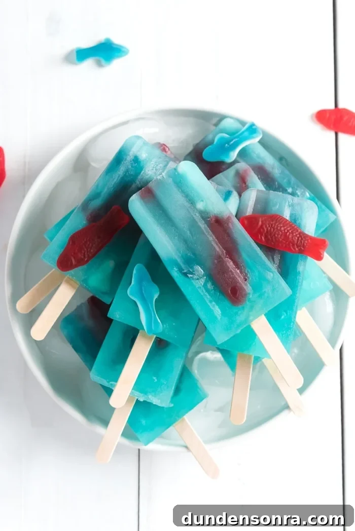 Blue lemonade popsicles stacked on a plate.