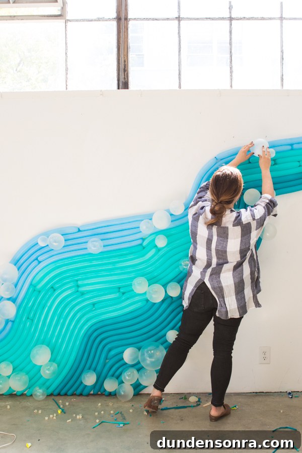Woman setting up a water inspired balloon wall. 
