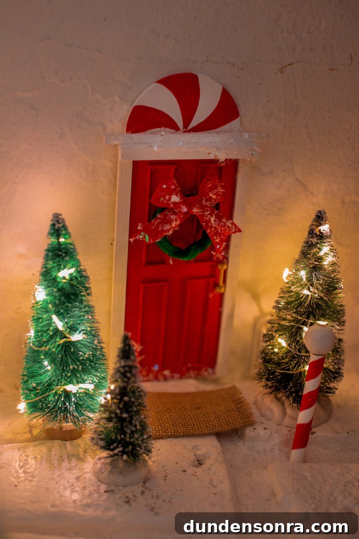 Elf door stuck to the wall with scene of trees and a north pole.