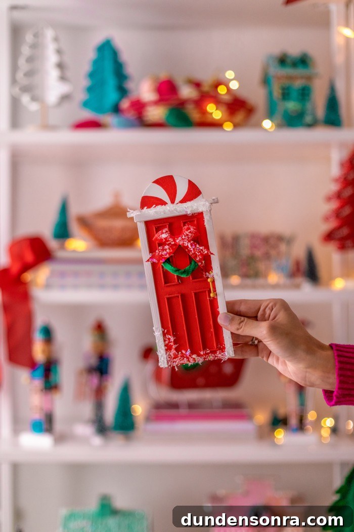 Hand holding the decorated elf door. 