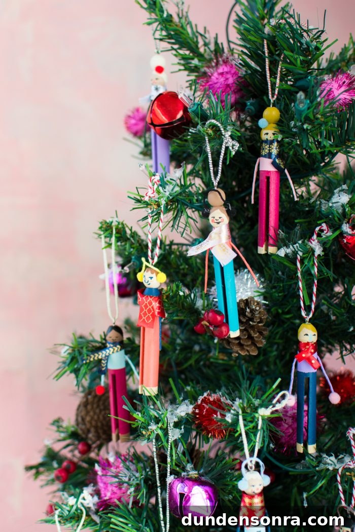 Handmade Christmas Ornaments Kids Can Make at Home 9 Clothespins decorated as people and made into ornaments hanging on a tree.