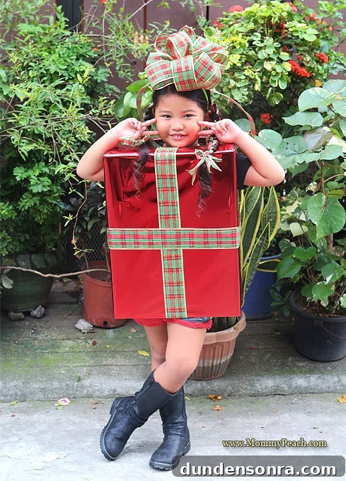 Christmas Present Costume Girl dressed as a Christmas present with a bow on her head.