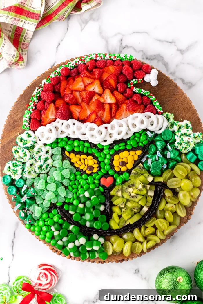 Grinch Charcuterie Board Fruits and candies in the shape of the Grinch on a wooden board.
