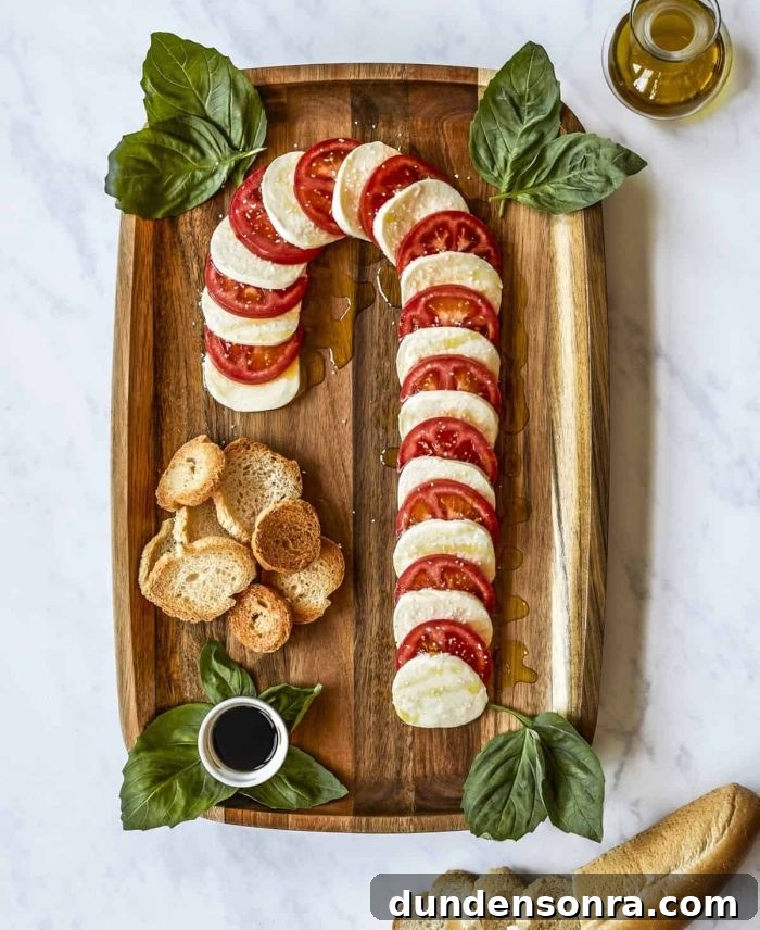 Candy Cane Charcuterie Board Tomatoes and cheese in the shape of a candy cane on a wooden board.