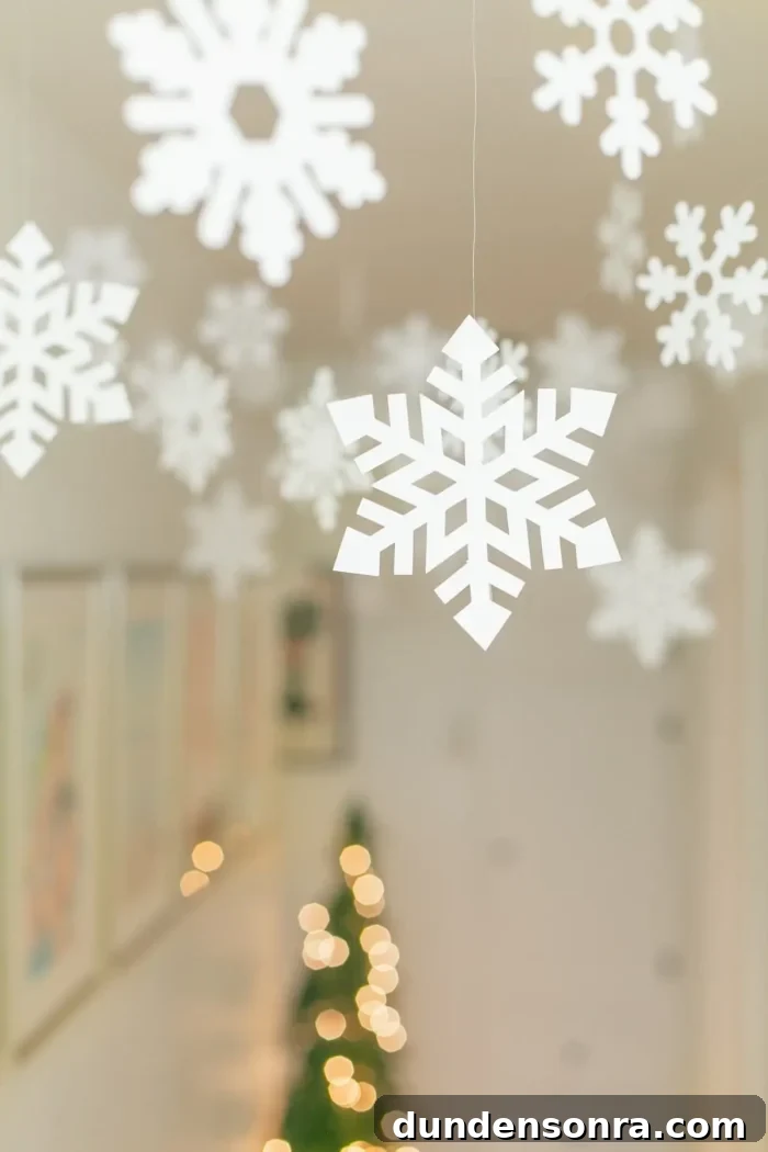 Snowflakes hanging from clear string on the ceiling. 