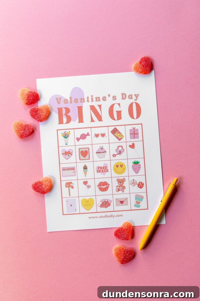Printed Valentine's day bingo on a pink background with heart gummies scattered on top.