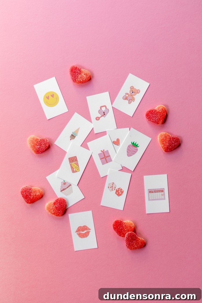 Calling cards cut out for bingo places on a pink background next to heart shaped gummy candies.