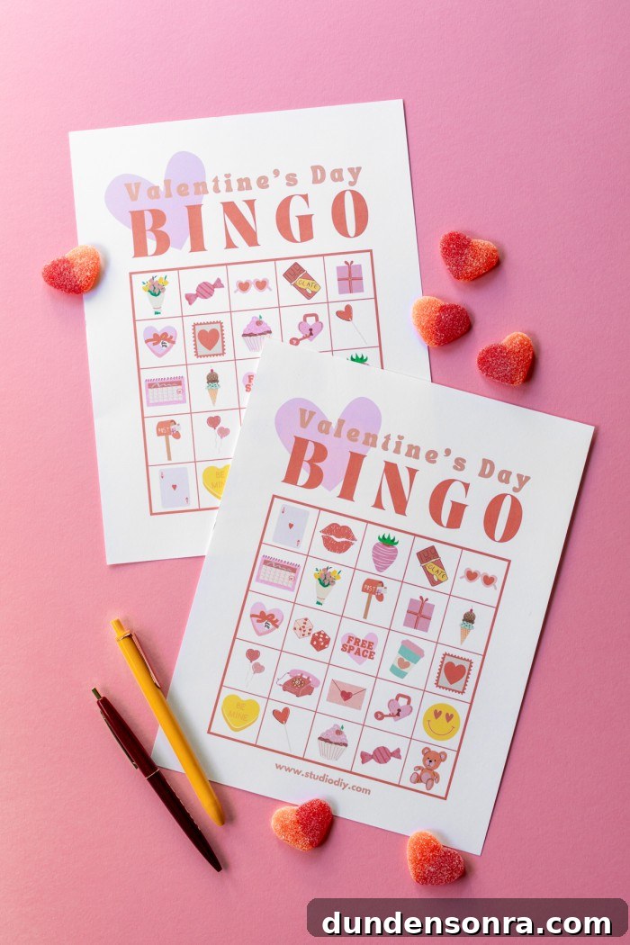 Two Valentine's Day bingo cards next to pens and gummy candies on a pink background.