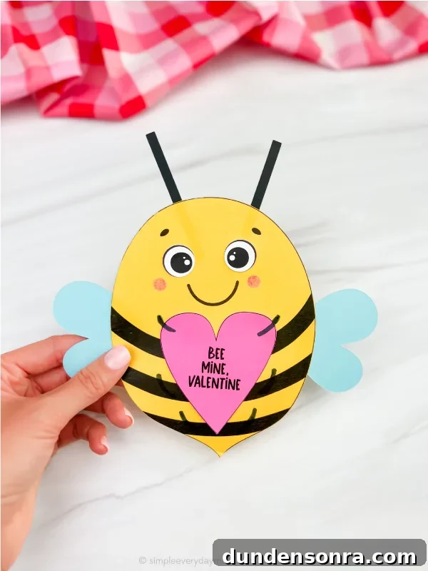 Hand holding a valentine shaped like a bee out of paper.