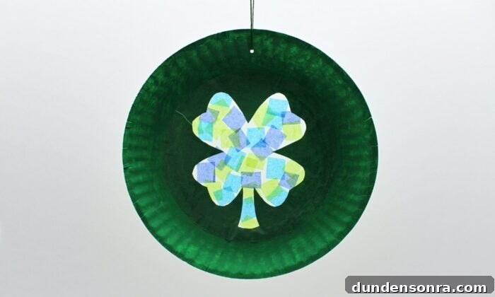 Shamrock Sun Catcher Paper plate painted green with a four leaf clover in the middle.