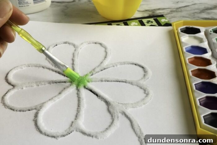 Shamrock Design Craft Shamrock made from glue and salt on a paper with a hand painting it green.