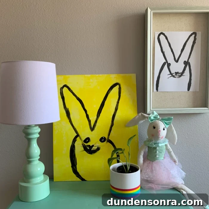 Two paintings of bunnies on a wall next to a night stand. 