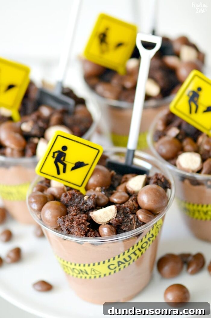 Chocolate dessert cups that have construction tape, signs and a little shovel as a spoon.
