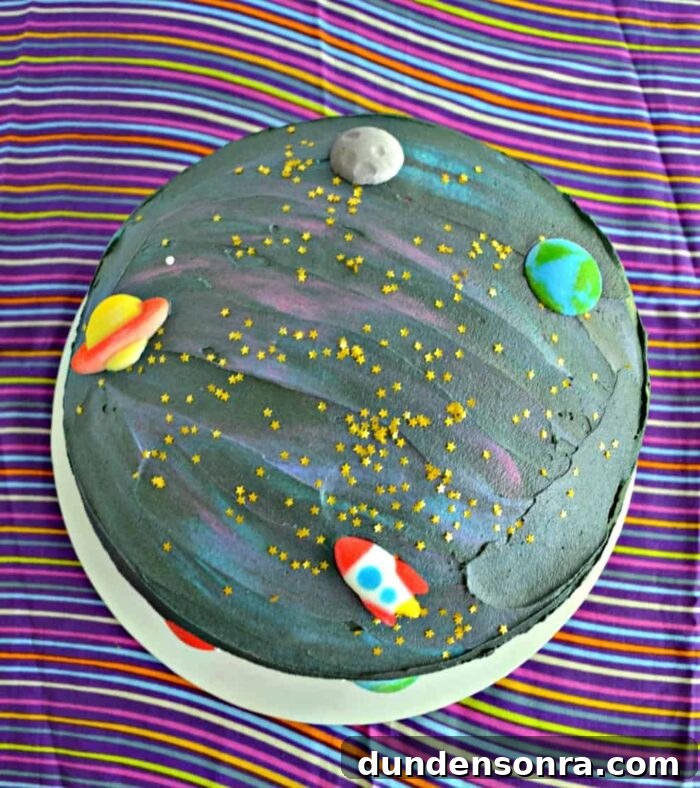 Black cake made to look like space with small planet figures. 