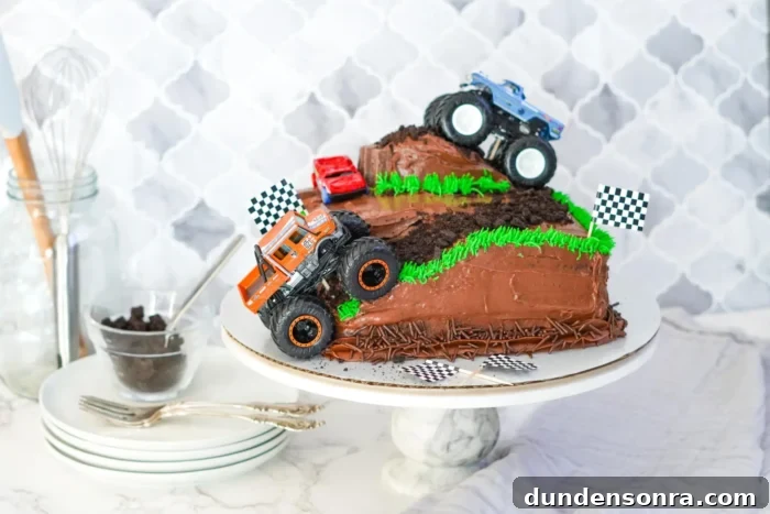 Chocolate cake with two monster trucks on it. 