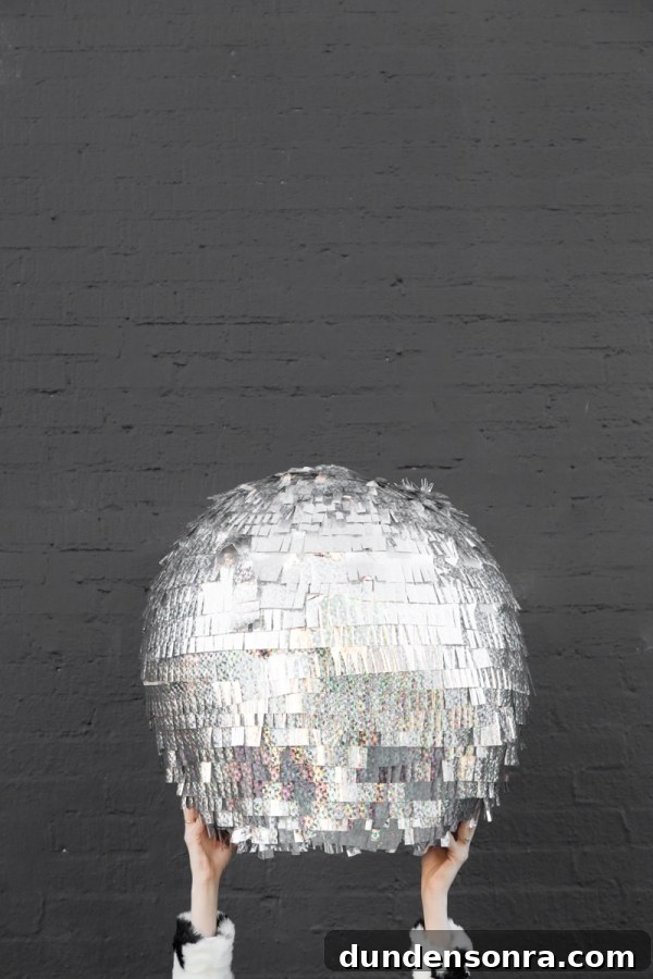 Hands holding a disco ball pinata in the air. 