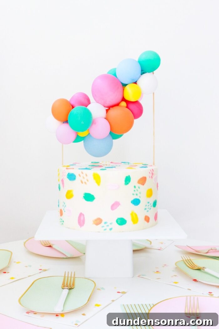 Birthday cake with a mini balloon topping on top. 