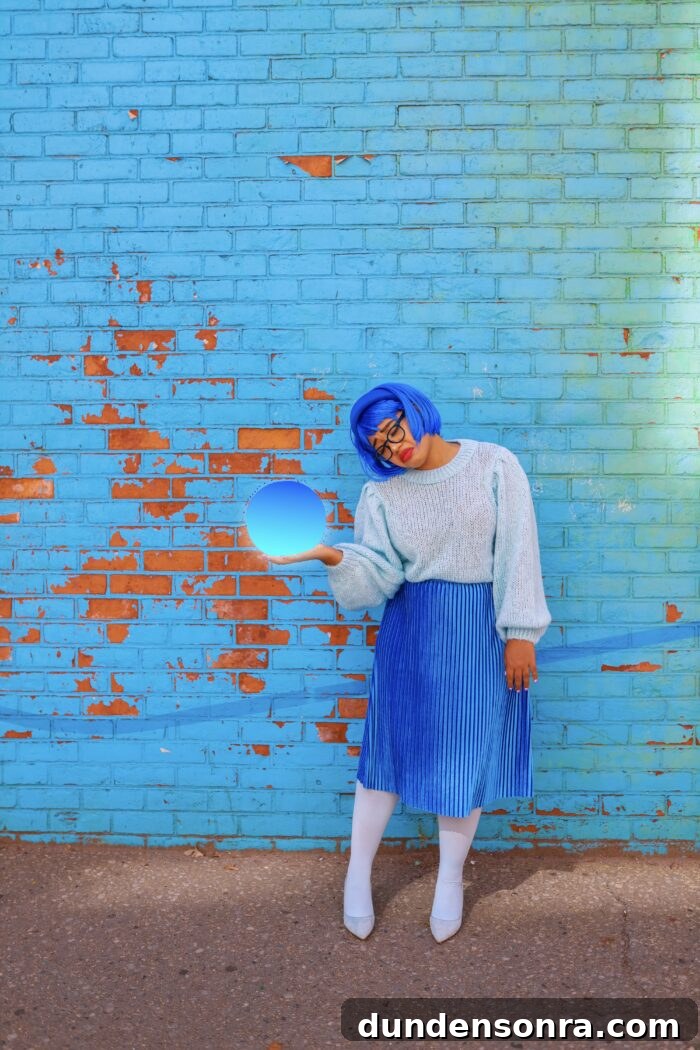 Woman dressed as "sadness" from Inside Out in front of a blue wall. 