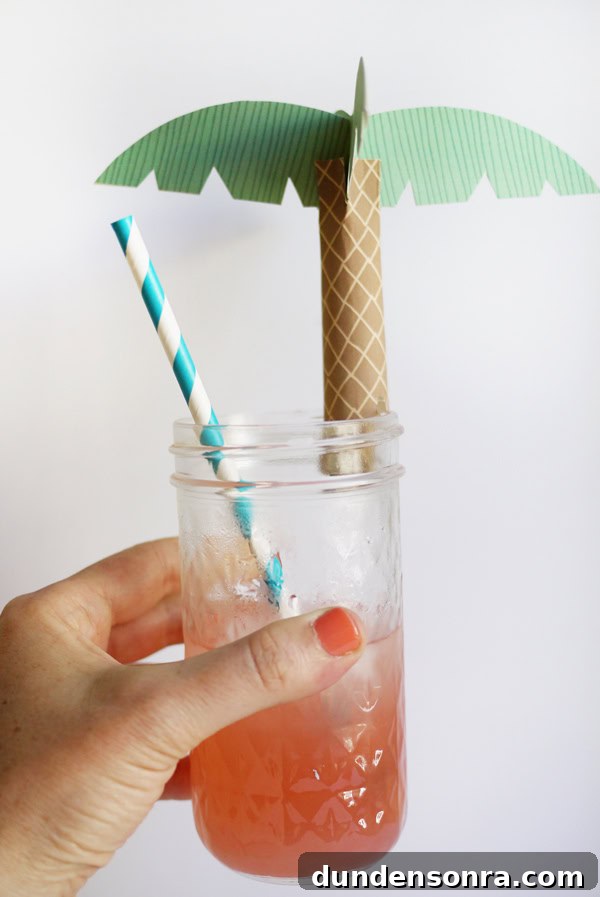 Drink Palms Hand holding a glass that is topped with a paper palm topper.