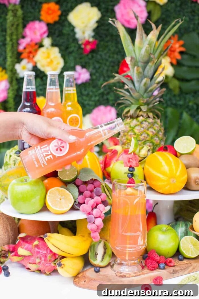Moana Fruit Juice Hand holding a bottle of soda and pouring it into a glass surrounded by tropical fruits.