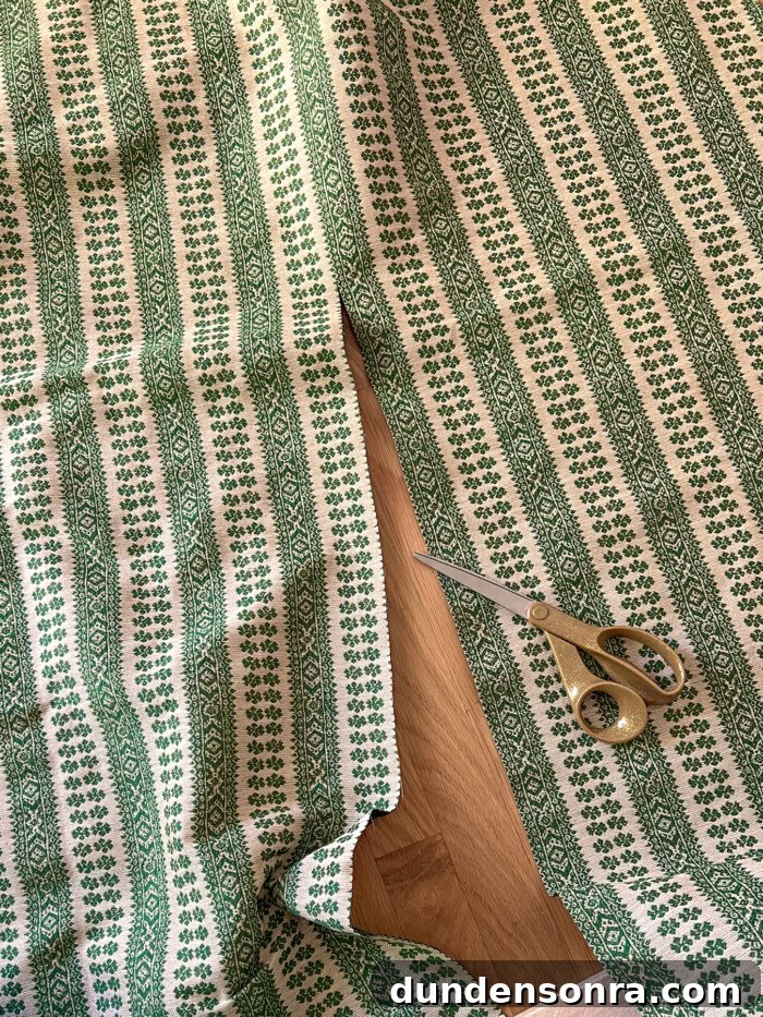 Green striped floral fabric being cut with gold scissors
