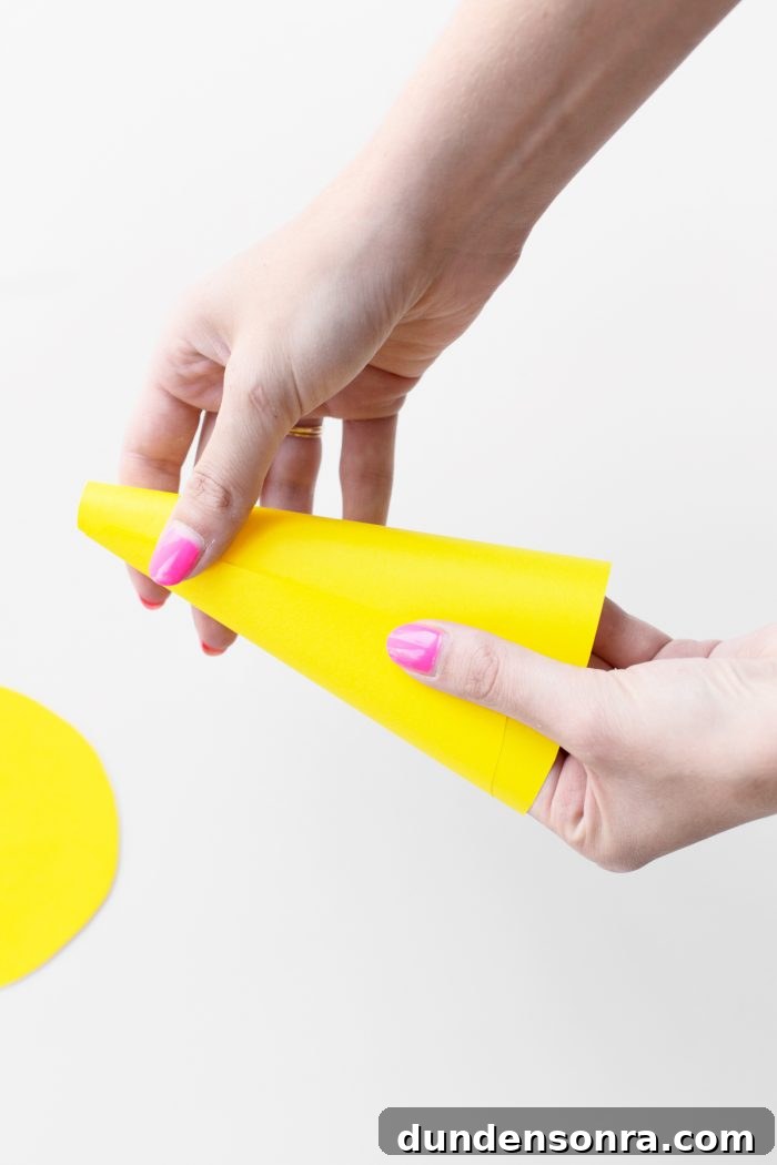 Someone folding yellow paper into a cone. 