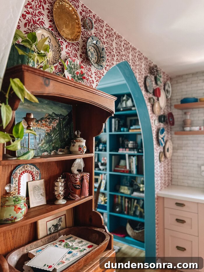 archway and hutch with red stripe wallpaper behind it in kitchen