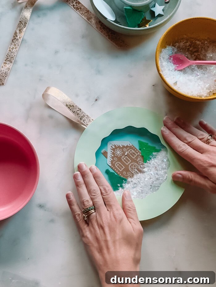 completing paper plate snow globe