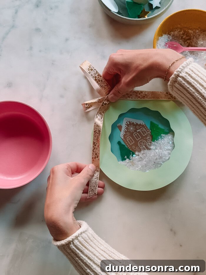 adding bow to paper plate snow globe